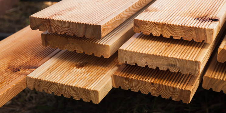 Nahaufnahme gestapelter geriffelter Terrassendielen aus naturbelassenem Holz im Aussenbereich